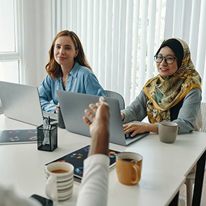 Women sitting in front of laptops smiling